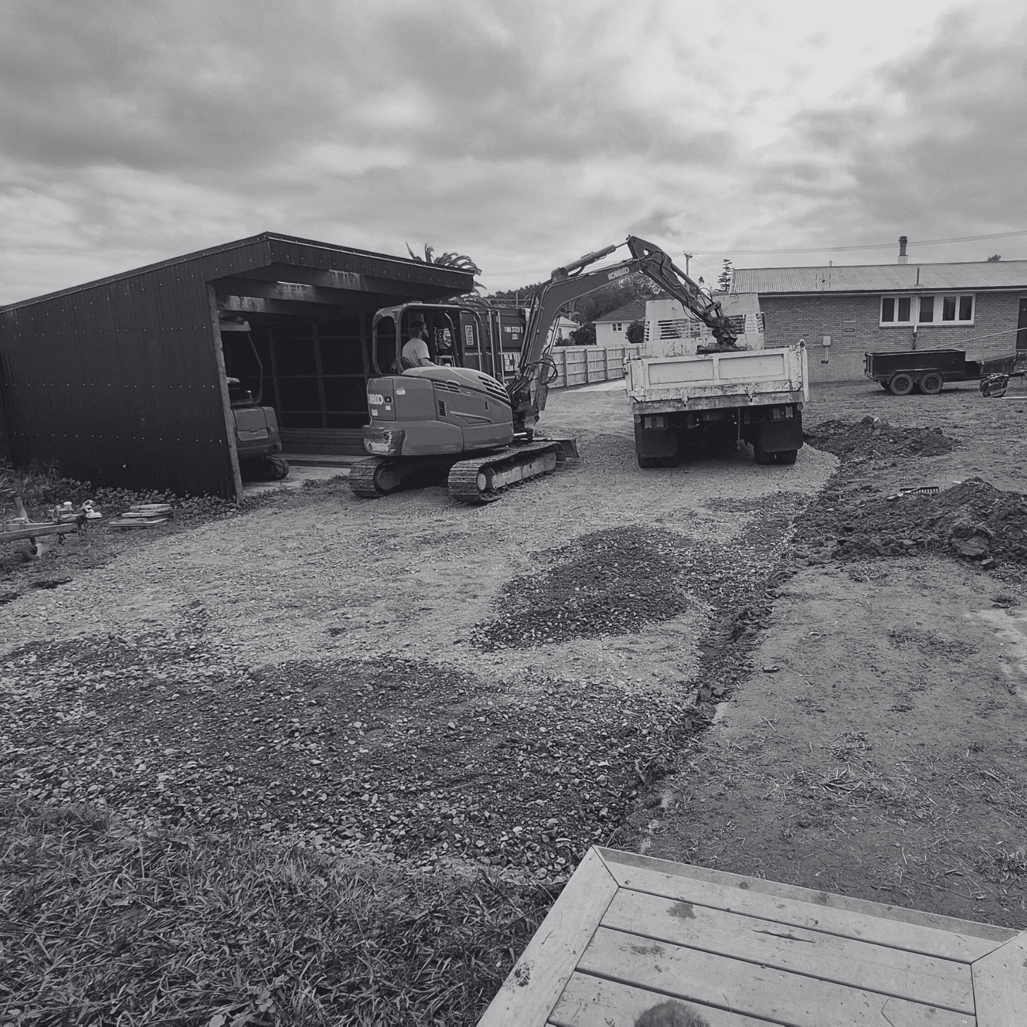Small excavator loading materials into a truck for driveway excavation project